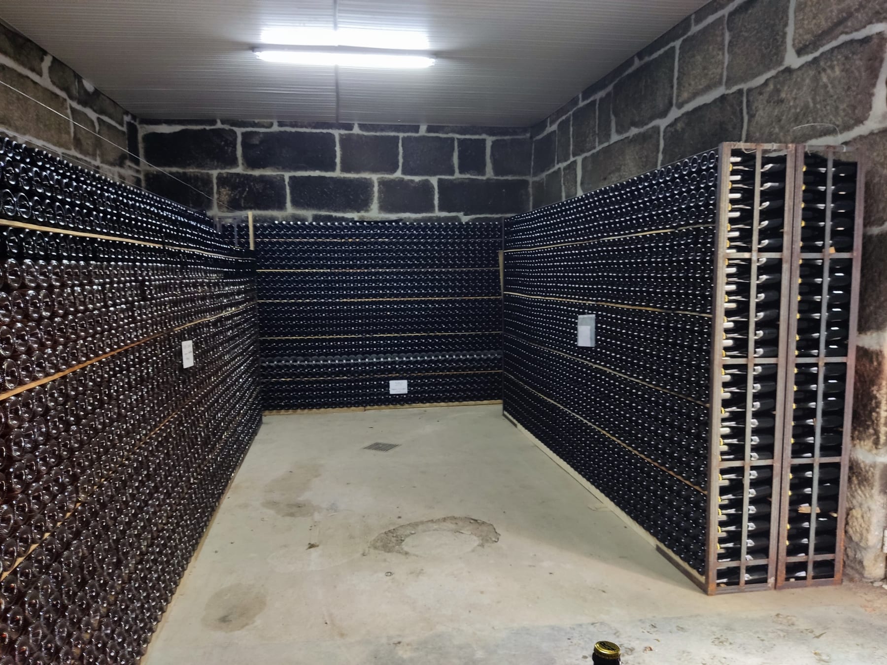 Cave de estágio com garrafas a repousar sobre borras